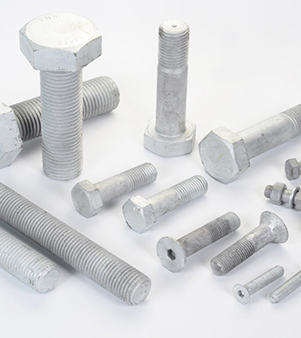 A Variety Of Bolts And Nuts Arranged On A White Surface, Showcasing Different Sizes And Shapes